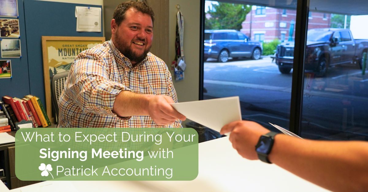Smiling man in a plaid shirt handing a document across the table during an in-person client meeting at Patrick Accounting, with the text